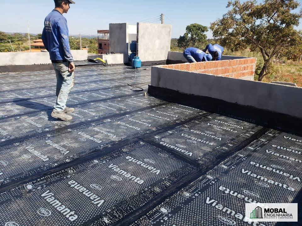 Equipe aplicando manta asfáltica em laje